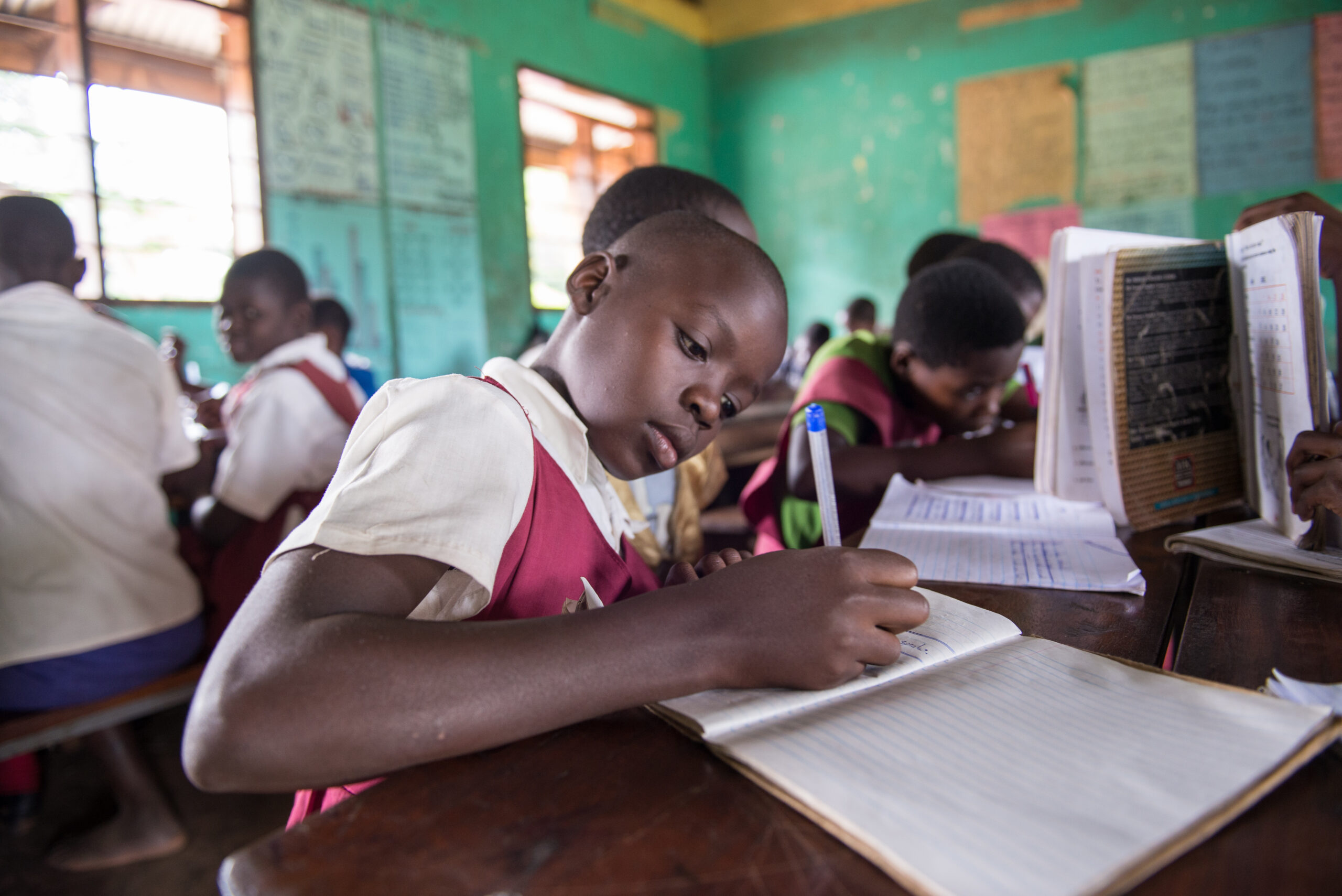 Girl writing in classroom, sub saharan africa. Coalition for good schools. 